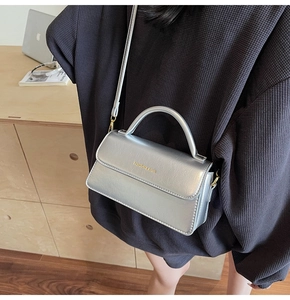 Detail of silver faux leather crossbody bag with FASHION & BAGS logo and sleek top handle