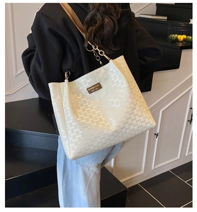 Détail du sac cabas blanc avec logo embossé et bandoulière chaîne sur mannequin femme
