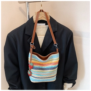 Detailed shot of multi-color woven bucket bag featuring cute strawberry pendant charms