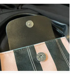 Close-up of silver magnetic snaps on striped tote bag with black textured leather trim