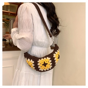 Detail of bohemian crochet crescent bag with sunflower pattern and woven shoulder strap