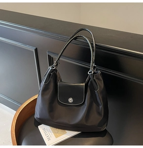 Detail of black nylon tote bag featuring white contrast stitching and silver metal lock