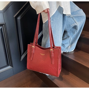 Detail of burgundy leather tote bag with gold buckle and adjustable shoulder strap