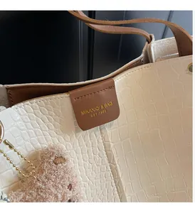 Detail of crocodile embossed cream tote bag with dark brown flap and gold logo lettering
