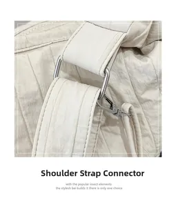 Detail of silver metal shoulder strap buckle on cream quilted crossbody messenger bag
