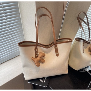 Detail of cream crocodile pattern tote bag with brown trim and cute dog charm pendant