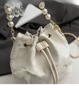 Detail view of cream bucket bag with floral embroidery and pearl handle clasp