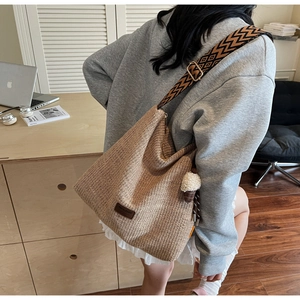 Dettaglio borsa hobo in paglia intrecciata con tracolla vintage e toppa in pelle marrone