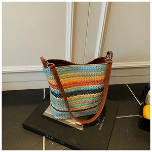 Detail of colorful striped woven bucket bag with brown leather strap and metal buckle
