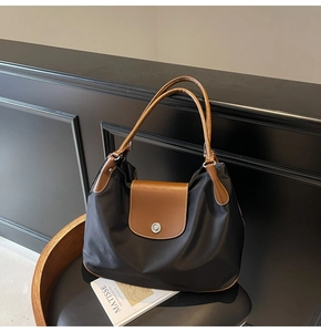 Detail of large nylon tote bag with leather trim and silver clasp on a chair