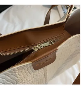 Detail of smooth gold zipper and crocodile texture on a large capacity tote bag