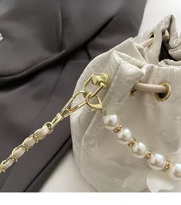 Detailed close-up of premium gold hardware and pearl strap on jacquard bucket bag