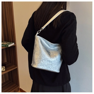 Rückansicht eines Modells mit silberner Plissee-Beuteltasche aus Metallic-Leder mit Riemen