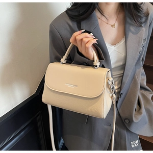 Detail of beige lychee pattern leather handbag with silver hardware and shoulder strap