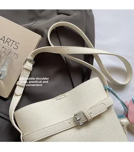 Detail of adjustable shoulder strap and horse charm on off-white lychee grain bucket bag