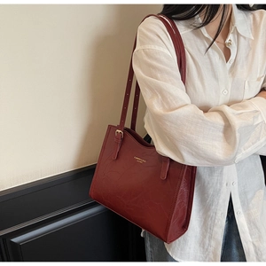 Detail of red leather tote bag with gold lettering and adjustable shoulder strap buckle