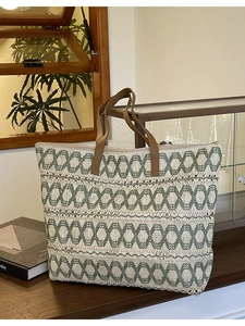 Large woven beach tote bag with green geometric patterns and brown leather handles
