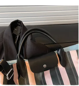 Detail of the pink and black striped tote bag featuring leather handles and metal snap closure