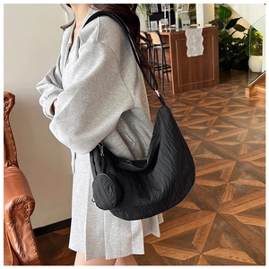 Close-up of black pleated dumpling bag with detachable coin purse pendant on shoulder