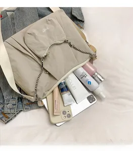 Close-up of beige canvas tote interior with matching round pouch and chain strap detail