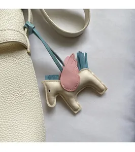Detail of a luxury pebble grain leather handbag featuring a colorful pegasus bag charm