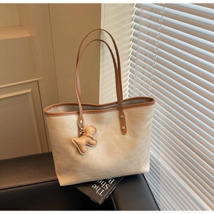 Detail of cream tote bag with crocodile texture, brown straps and cute puppy charm