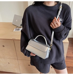 Detail of silver metallic leather handbag with a thin shoulder strap and fashion logo