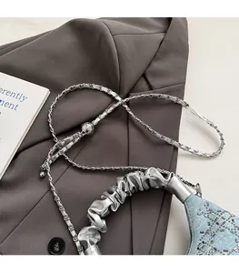 Close-up of light blue denim handbag with rhinestones and silver woven chain strap
