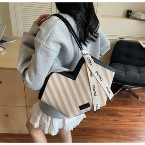Detail of large woven tote bag with V-cut opening and branded strap in office setting