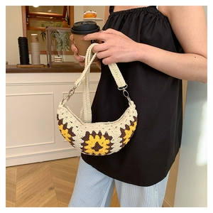 Close-up of handmade crochet crescent bag with sunflower pattern and silver metal hardware