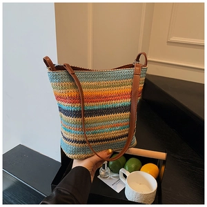 Macro view of a colorful woven bucket bag featuring vibrant rainbow stripes and leather strap
