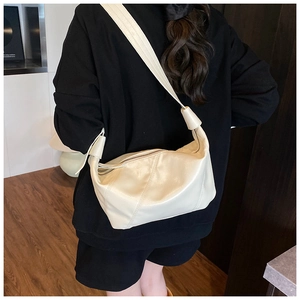 Vue détaillée du sac dumpling en cuir crème porté en bandoulière avec nœud décoratif