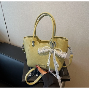 Détail du cabas en cuir grainé vert clair avec nœud en dentelle et perle élégante