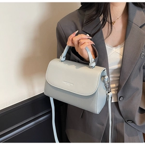Detail of light blue crossbody bag with lychee texture and silver metal hardware