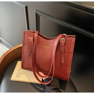 Detail of vintage red tote bag with wrinkled texture and gold-tone buckle strap