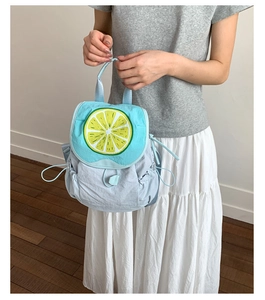 Close-up of a sky blue nylon backpack featuring a bright yellow lemon slice design