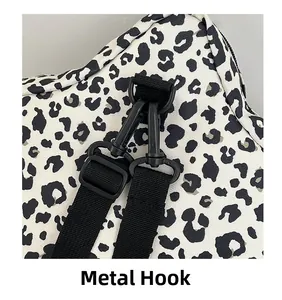 Detail of matte black metal hook and durable woven strap on leopard print canvas bag