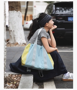 Detail view of large nylon tote bag in bright yellow and light blue color block design