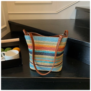 Detailed shot of rainbow woven straw tote bag with brown leather straps on steps