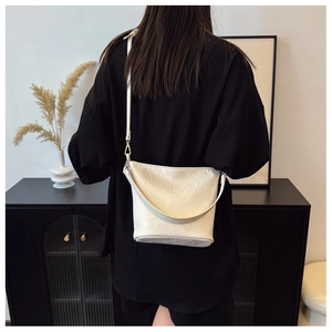 Detail der cremeweißen Eimer-Tasche mit silbernen Beschlägen an der Modelseite