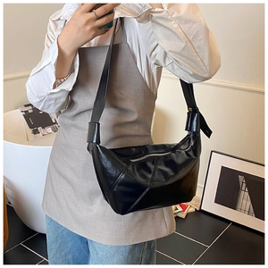 Détail du sac à main noir en similicuir avec coutures géométriques et bandoulière nouée