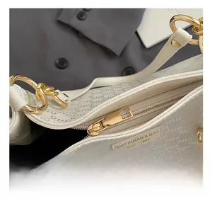 Détail du cabas blanc montrant les anneaux dorés et l'étiquette de marque en cuir