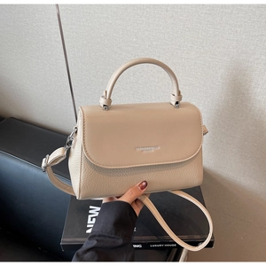Detail of beige pebble leather handbag showing top handle and adjustable shoulder strap