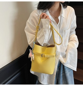 Detail view of a yellow lychee textured bucket bag with elephant charm and silver buckle