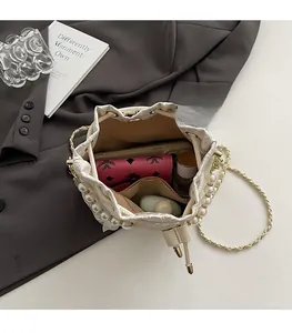 Internal view of a pearl-trimmed bucket bag showing space for phone and perfume