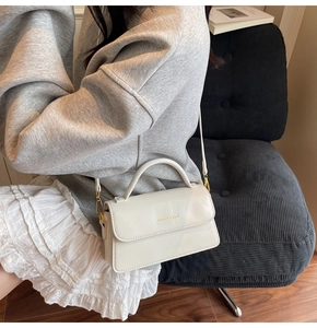 Close-up of cream leather crossbody bag with FASHION & BAGS gold lettering detail