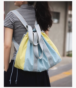 Detail of blue and yellow drawstring backpack made of lightweight nylon with gray straps