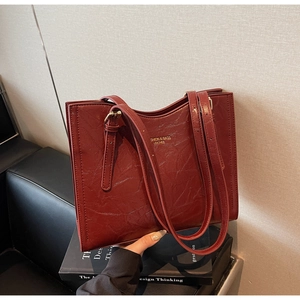 Macro detail of wine red tote bag showing vintage leather texture and gold metal accents