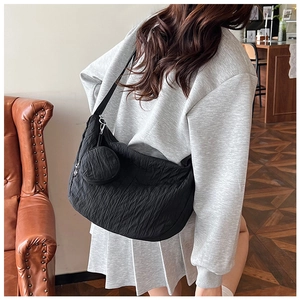 Detail of black pleated crescent bag with matching mini round pouch on shoulder strap