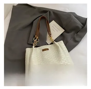 Détail du sac cabas en cuir gaufré crème avec anses en cuir marron et chaîne dorée chic
